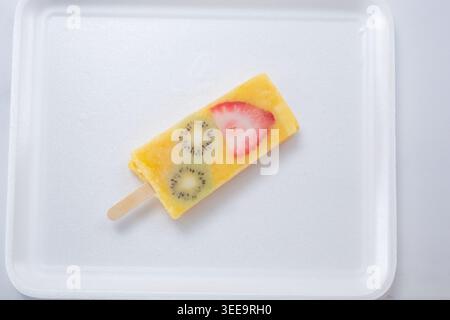 Ein Blick von oben auf eine Ananasorange Mango paleta mit Kiwi und Erdbeerscheiben. Stockfoto