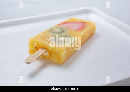 Blick auf eine Ananasorange Mango paleta mit Kiwi- und Erdbeerscheiben. Stockfoto