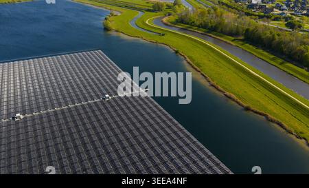 Luftaufnahme eines großen schwimmenden Solarparks auf einem See mit grünen grasbewachsenen Ufern und einem gewundenen Kanal in Zwolle, Overijssel, Niederlande. Stockfoto