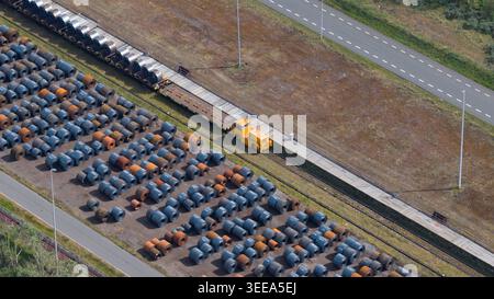 Luftaufnahme des Industriegeländes Tata Steel mit Reihen von Stahlspulen und einem gelben Transportfahrzeug auf Gleisen in Velsen-Noord, Noord-Holland, N Stockfoto