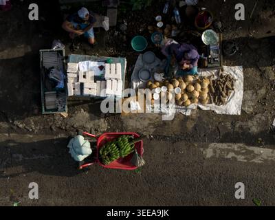 Blick aus der Vogelperspektive auf den traditionellen Markt Pasar Kembang Klaten mit Händlern, die Kokosnüsse, Bananen und lokale Produkte auf der Straßenseite in Klaten, Central, verkaufen Stockfoto