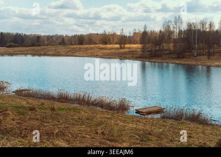 Kleines Holzboot, Das Am Shore Edge Verankert Ist, Verwitterter Hull Ruht Neben Reeds Am Calm Lake, Reflektierendes Wasser Und Ruhige Morgenstimmung Laden Zur Besinnung Ein Stockfoto