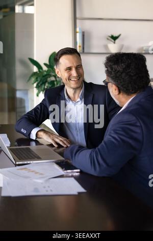 Glückliche Geschäftsleute diskutieren während der Besprechung im Büro über Projektergebnisse Stockfoto