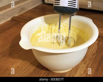 Zubereitung einer Mischung oder eines Teigs mit einem elektrischen Handrührgerät in einer Küche, wobei das Backen, Kochen und die Zubereitung von Speisen angezeigt wird Stockfoto