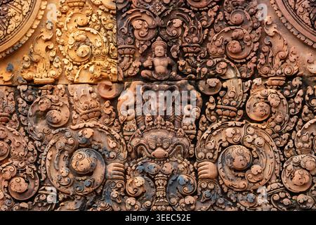Makroaufnahme mit außergewöhnlicher rosa Sandsteinschnitzerei in Banteay Srei. Das Basrelief zeigt den Gott Indra auf seinem Elefanten Airavata, umgeben von komplexem flo Stockfoto