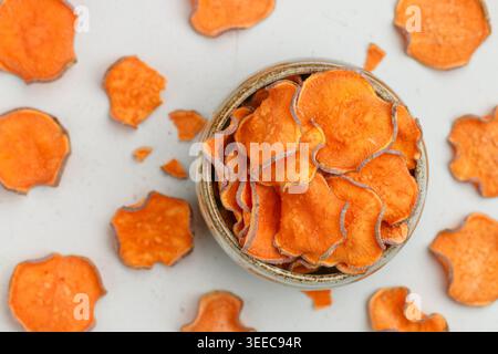 Gesunde Bio Süßkartoffelchips in einer Schüssel auf einem Steinhintergrund. Vegetarische und vegane Vorspeise. Diät. Ein nützlicher Snack. Selektiver Fokus, Draufsicht Stockfoto