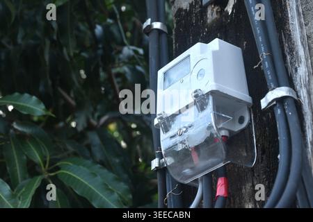 Digitales elektrisches Messgerät auf Holzbrett am Pol vor dem Hausbewohner Stockfoto