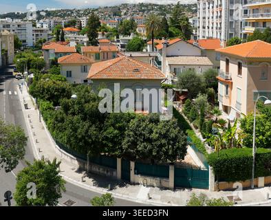 Panoramablick auf das Wohnviertel in Nizza mit traditionellen orange gefliesten Dächern und üppigen grünen Gärten. Malerische urbane Landschaft zeigt historische Geschichte Stockfoto