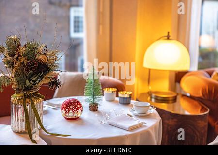 Festliche und elegante Weihnachtsdekoration in einem gemütlichen Restaurant mit warmem goldenem Bokeh-Hintergrund Stockfoto