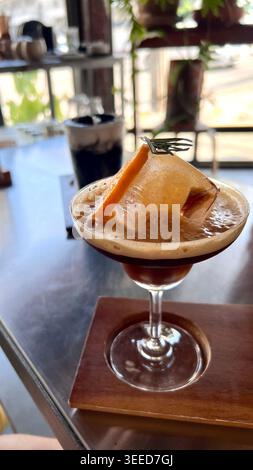 Iced Espresso Tonic mit Orangengarnitur in Coupé Glas, erfrischender Eiskaffee mit frischem Orangenscheiben Stockfoto