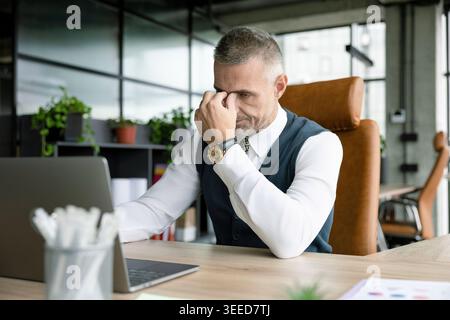 Reifer Geschäftsmann mit Papierkram. Ernsthafter Geschäftsmann im Amt. Geschäftsmann mit Papierkram. Geschäftsmann fühlt sich traurig und überarbeitet. Geschäftsproblem Stockfoto