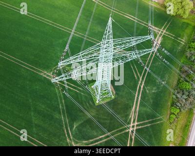 Luftaufnahme des Hochspannungs-Stromleitungsturms über grünen landwirtschaftlichen Feldern Stockfoto