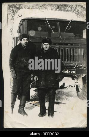 Zwei Fahrer standen in den 1970er Jahren bei Wintertransporten neben einem GAZ-66-Lkw Authentisches sowjetisches Foto. Stockfoto