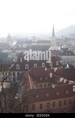 Blick auf historische, rot gekachelte Dächer und Kirchtürme unter einem trüben Morgenhimmel in der Altstadt von Prag, Prag, Tschechien. Stockfoto