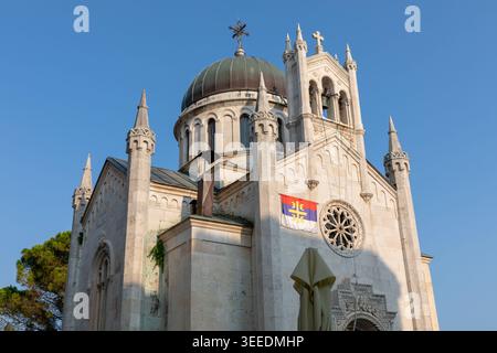 Herceg Novi, Montenegro - 31. Juli 2025: Blick auf eine orthodoxe Kirche mit Kuppel, Glockenturm und serbischer Flagge an der Fassade in Herceg Novi, Mon Stockfoto