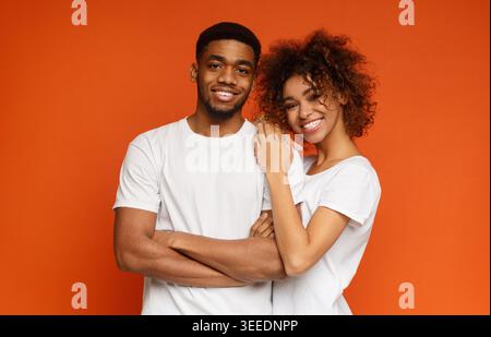 Junge afroamerikanische Paare posieren auf orangefarbenem Hintergrund Stockfoto