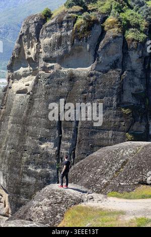 Einsamer Reisender, der auf einer zerklüfteten Klippe mit Blick auf die majestätischen, majestätischen Steinsäulen von meteora, griechenland, steht. Epische Landschaftsfotografie im Handumdrehen Stockfoto
