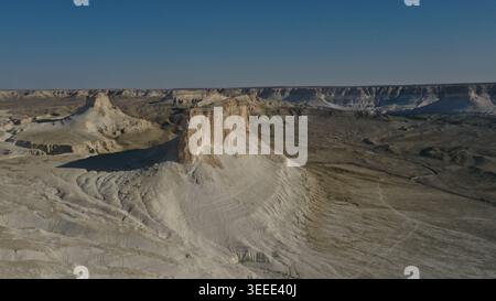Aus der Vogelperspektive werden majestätische Sandsteinkuppen erfasst, die dramatisch aus weiten Wüstenebenen unter einem wolkenlosen azurblauen Himmel auftauchen und rugge zeigen Stockfoto