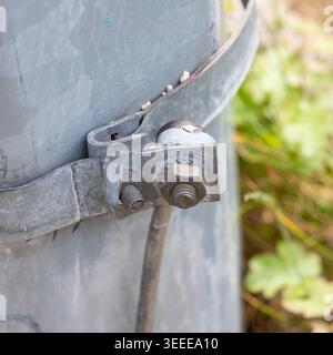 Metallschelle, die einen Draht mit einem Stützmast verbindet, mit Schrauben und Muttern im Freien Stockfoto