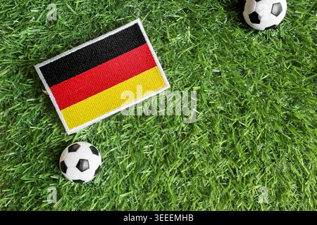 Flaches Lagen der deutschen Nationalflagge und der Fußballbälle auf grünem Rasen. Symbolisch für Sportstolz und internationalen Fußballturnierwettbewerb. Stockfoto