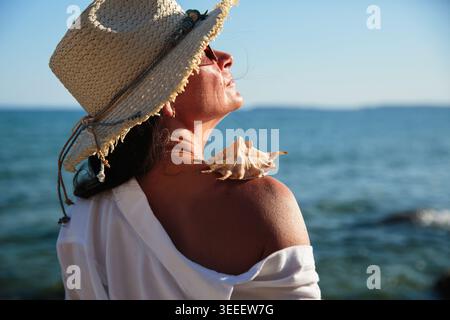 Entspannte Reife Frau genießt Sonnenlicht am Meer Nahaufnahme Stockfoto
