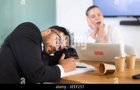Müde Büroangestellte, die am Arbeitsplatz ein Nickerchen machen Stockfoto