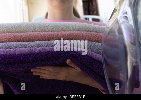 Frau, die bunte saubere Handtücher in die Waschmaschine zu Hause, Wäschetag Hausroutine aus nächster Nähe vom Trockner lädt Stockfoto