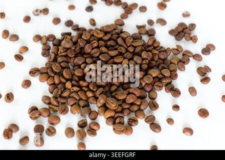 Eine Vollformataufnahme von oben nach unten mit zahlreichen gerösteten Kaffeebohnen auf einem sauberen weißen Hintergrund, die ihre satte braune Farbe und Textur zeigen. Stockfoto