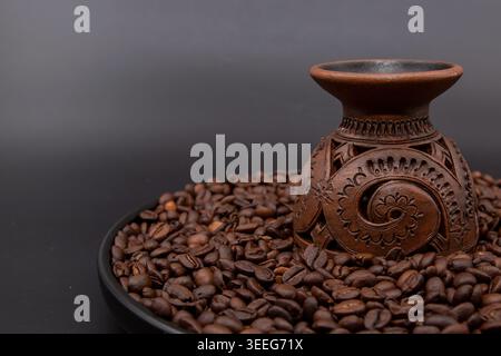 Traditionelle Tonkaffeekanne auf gerösteten Kaffeebohnen mit dunklem Hintergrund Stockfoto