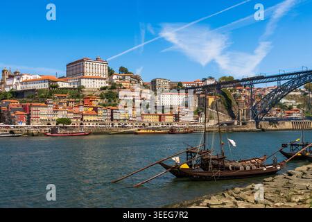 Traditionelle portugiesische Ragelo-Weinboote, die auf dem Fluss Douro mit der farbenfrohen Ribeira-Uferpromenade und der Dom Luis I-Brücke im Hintergrund, Porto vor Anker liegen Stockfoto