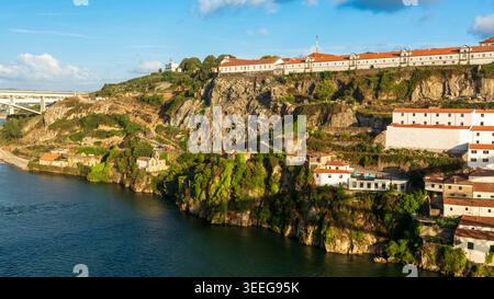 Malerischer Blick auf die steilen felsigen Klippen entlang des Flusses Douro in Porto, mit weiß getünchten historischen Klostergebäuden, die dramatisch oben und lu thront Stockfoto