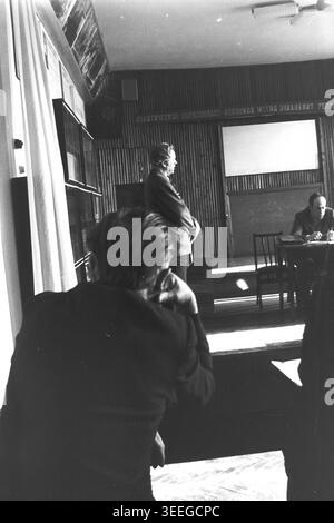 Slaviansk, 1983. Konferenzsaal der Armature-Isolator Factory (AIZ). Ein Mann steht auf dem Podium und hält eine Rede in der Nähe des Präsidiumstisches, aus der Perspektive des sitzenden Publikums betrachtet. Dieses Vintage-Schwarz-weiß-Foto fängt die authentische Atmosphäre der Epoche ein und spiegelt die täglichen Aktivitäten und Industriekultur der Region während der Sowjetzeit wider. Es dient als wertvolles historisches Dokument der lokalen Gemeinde, das das visuelle Gedächtnis der Menschen und ihres täglichen Lebens bewahrt und einen friedlichen Donbass zeigt. Stockfoto