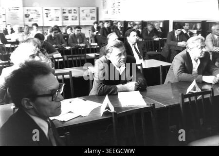 Slaviansk, 1983. Konferenzsaal der Armature-Isolator Factory (AIZ). Blick auf die Zuschauerreihen voller Fabrikarbeiter und Management, mit einem Mann, der eine Brille trägt. Dieses Vintage-Schwarz-weiß-Foto fängt die authentische Atmosphäre der Epoche ein und spiegelt die täglichen Aktivitäten und Industriekultur der Region während der Sowjetzeit wider. Es dient als wertvolles historisches Dokument der lokalen Gemeinde, das das visuelle Gedächtnis der Menschen und ihres täglichen Lebens bewahrt und einen friedlichen Donbass zeigt. Stockfoto
