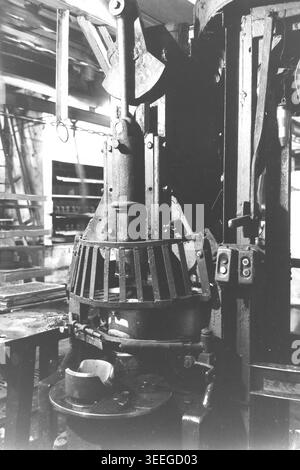 Slaviansk, 1983. In einer Werkstatt in der Armature-Insulator Factory (AIZ). Gezeigt wird eine schwere vertikale mechanische Pressmaschine, die mit einem Metallschutzgitter um den Arbeitsbereich und seitlich angebrachten Steuerknöpfen ausgestattet ist. Dieses Vintage-Schwarz-weiß-Foto fängt die authentische Atmosphäre der Epoche ein und spiegelt die täglichen Aktivitäten und Industriekultur der Region während der Sowjetzeit wider. Es dient als wertvolles historisches Dokument der lokalen Gemeinde, bewahrt das visuelle Gedächtnis und zeigt einen friedlichen Donbass. Stockfoto