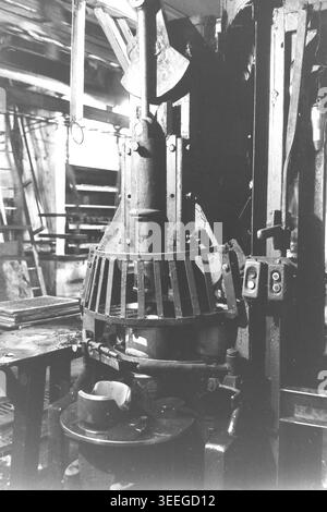 Slaviansk, 1983. In einer Werkstatt in der Armature-Insulator Factory (AIZ). Gezeigt wird eine schwere vertikale mechanische Pressmaschine, die mit einem Metallschutzgitter um den Arbeitsbereich und seitlich angebrachten Steuerknöpfen ausgestattet ist. Dieses Vintage-Schwarz-weiß-Foto fängt die authentische Atmosphäre der Epoche ein und spiegelt die täglichen Aktivitäten und Industriekultur der Region während der Sowjetzeit wider. Es dient als wertvolles historisches Dokument der lokalen Gemeinde, bewahrt das visuelle Gedächtnis und zeigt einen friedlichen Donbass. Stockfoto