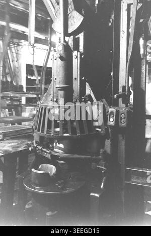 Slaviansk, 1983. In einer Werkstatt in der Armature-Insulator Factory (AIZ). Gezeigt wird eine schwere vertikale mechanische Pressmaschine, die mit einem Metallschutzgitter um den Arbeitsbereich und seitlich angebrachten Steuerknöpfen ausgestattet ist. Dieses Vintage-Schwarz-weiß-Foto fängt die authentische Atmosphäre der Epoche ein und spiegelt die täglichen Aktivitäten und Industriekultur der Region während der Sowjetzeit wider. Es dient als wertvolles historisches Dokument der lokalen Gemeinde, bewahrt das visuelle Gedächtnis und zeigt einen friedlichen Donbass. Stockfoto