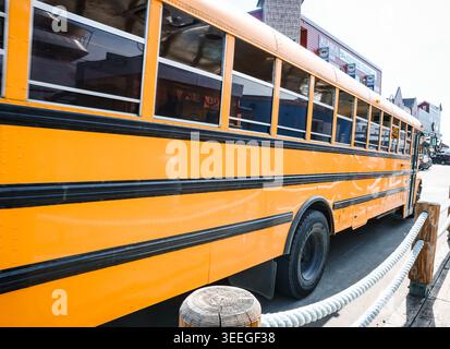 Ketchikan, Alaska, USA - 19. Juli 2025: Ein klassischer gelber amerikanischer Schulbus, der als Touristenbus umfunktioniert wurde und entlang der Uferpromenade in der Innenstadt von K parkt Stockfoto