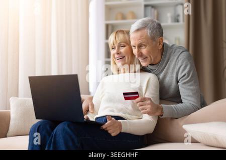 Ältere Ehepaare kaufen online mit Laptop und Kreditkarte zu Hause ein Stockfoto
