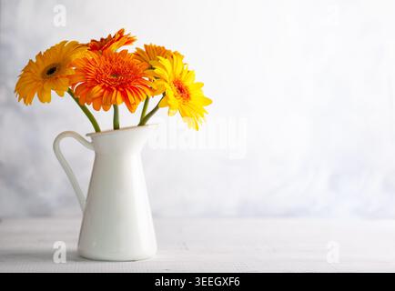 Wunderschöner Blumenstrauß aus roten und gelben Blumen in weißer Vase auf Holztisch, Vorderansicht. Herbststillleben mit Blumen. Stockfoto