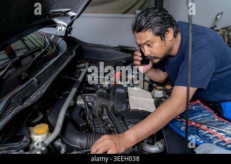 Konzentrierter junger Mann, der Motorkomponenten und Flüssigkeitsstände im Auto während der routinemäßigen Wartung von Heimwerkerfahrzeugen zu Hause überprüft. Stockfoto
