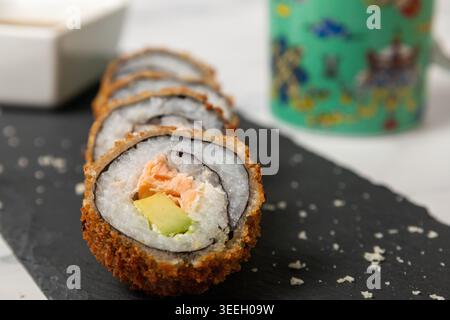 Eine hochgezogene Studioaufnahme mit fünf selbstgemachten, frittierten Sushi (Tempura-Rollen) gefüllt mit frischem Lachs und Avocado. Die Rollen sind diag angeordnet Stockfoto