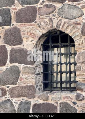 Rustikale Steinmauer mit kleinem Gitterfenster Stockfoto