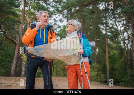 Wandertourismus. Senior Paar Mann Frau, die auf einer Karte auf Papier sucht, genießt Wanderungen im Wald. Glückliche alte Leute Backpacker Wanderer genießen Wandern Wandertourismus Aktivurlaub Schönheit der Natur Stockfoto