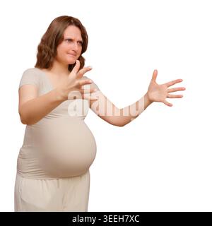 Schwangere Frau, die mit Händen Gesten macht, als ob sie etwas misst oder ein unsichtbares Objekt hält. Werdende Mutter, die vor weißem Hintergrund steht. Preg Stockfoto