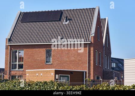 Nachhaltige Wohnarchitektur mit Solarpaneelen auf Einem modernen Ziegelhausdach in Einem niederländischen Viertel, erneuerbar Stockfoto