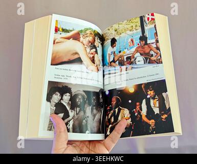 Offene Seiten der Autobiografie von Keith Richards, die Vintage-Farbfotos des Gitarristen Rolling Stone zeigt, der das dicke Buch hält. Stockfoto