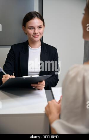 Junge kaukasische Frau, die Dokumente im modernen Büro überprüft Stockfoto