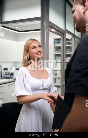 Junge kaukasische Frau schüttelt Hand mit einem Mann im Amt Stockfoto