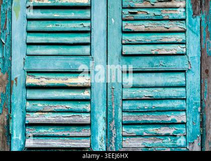 Nahaufnahme eines Satzes traditioneller Fensterläden mit Lamellen in leuchtendem, verwittertem Türkisgrün, George Town, Penang, Malaysia Stockfoto