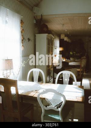 Im Ott and Matilda Cafe, Estland, befindet sich ein sonnendurchflutetes Vintage-Café mit Holztisch, weißen Stühlen und Spitzenläufern Stockfoto